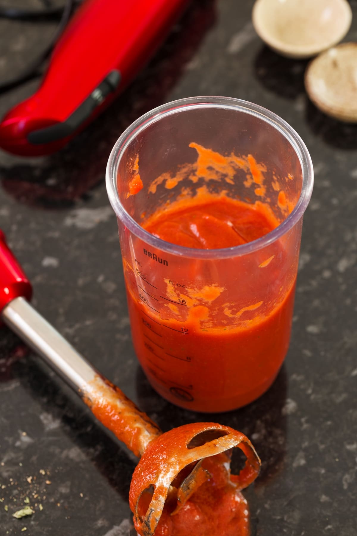 Mixing tomato sauce and condiments with an immersion blender.