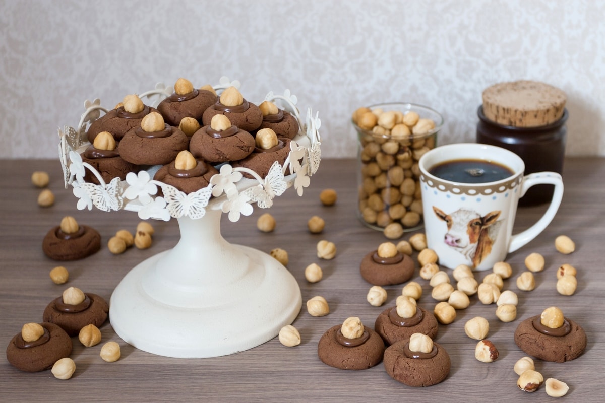 Nutella thumbprint cookies serves with coffee and whole hazelnuts.
