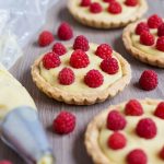 Home-made custard tarts decorated with freshly picked raspberries
