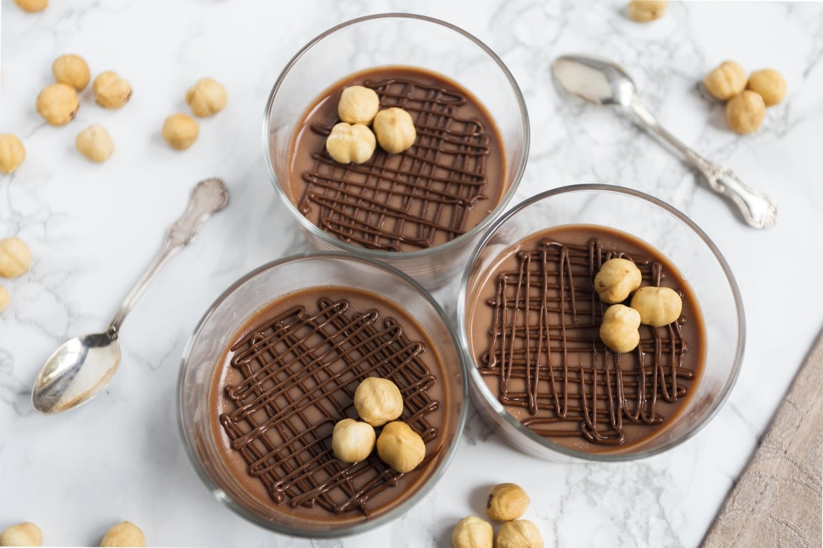 Nutella panna cotta decorated with piped nutella and whole hazelnuts.