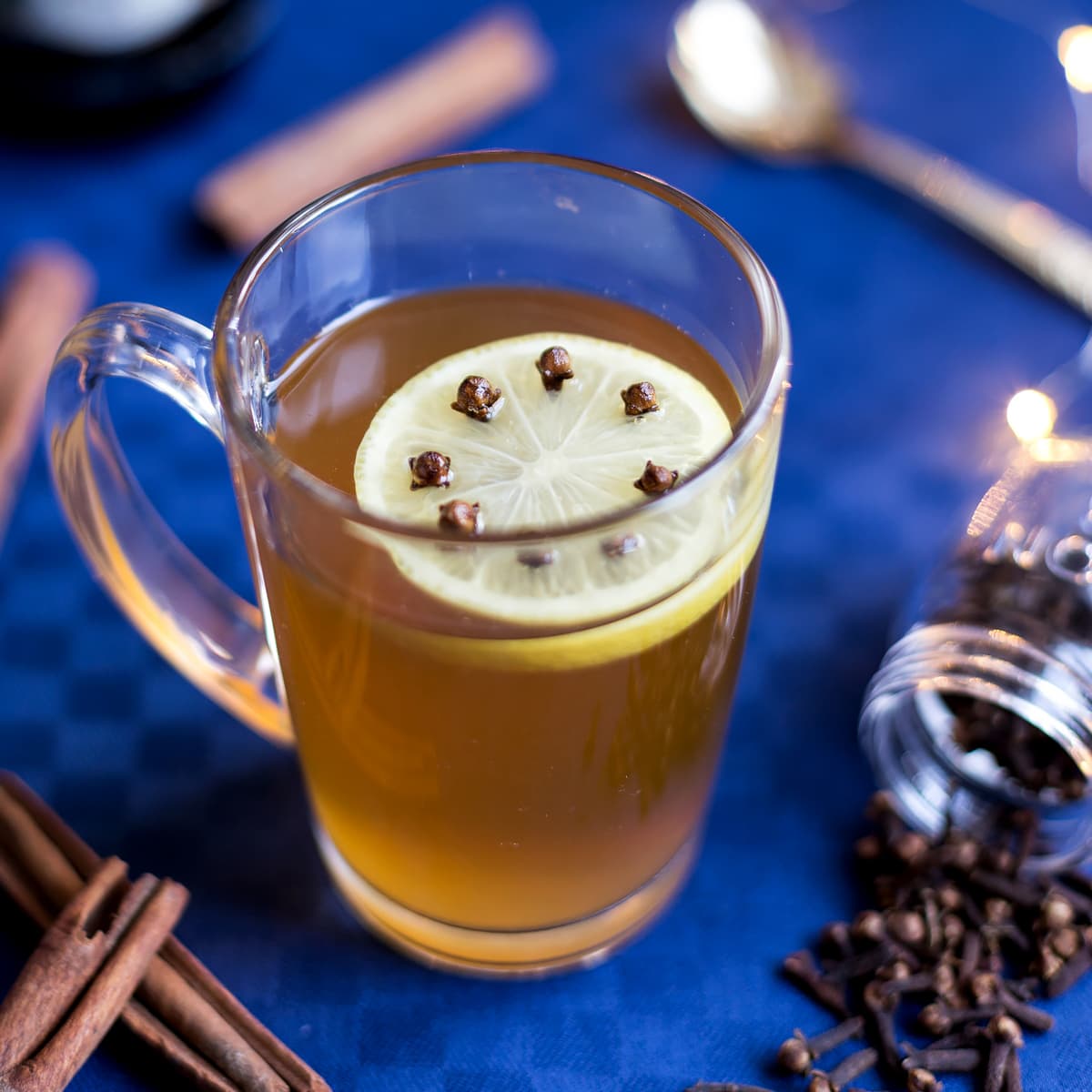 Closeup showing clove decorated lemon slice floating on top of hot beer drink.