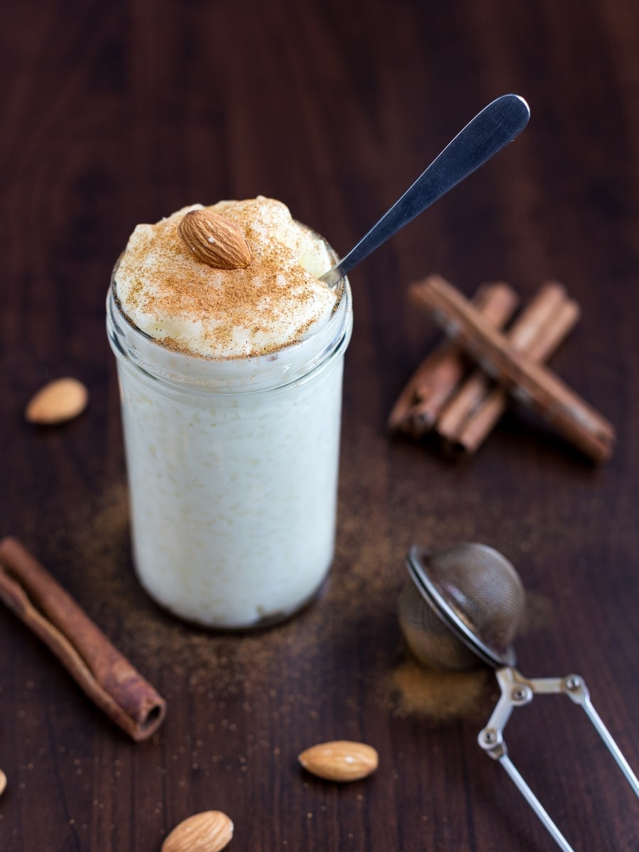 Risgrynsgröt rice porridge served in a jar, topped with cinnamon powder and a whole almond.