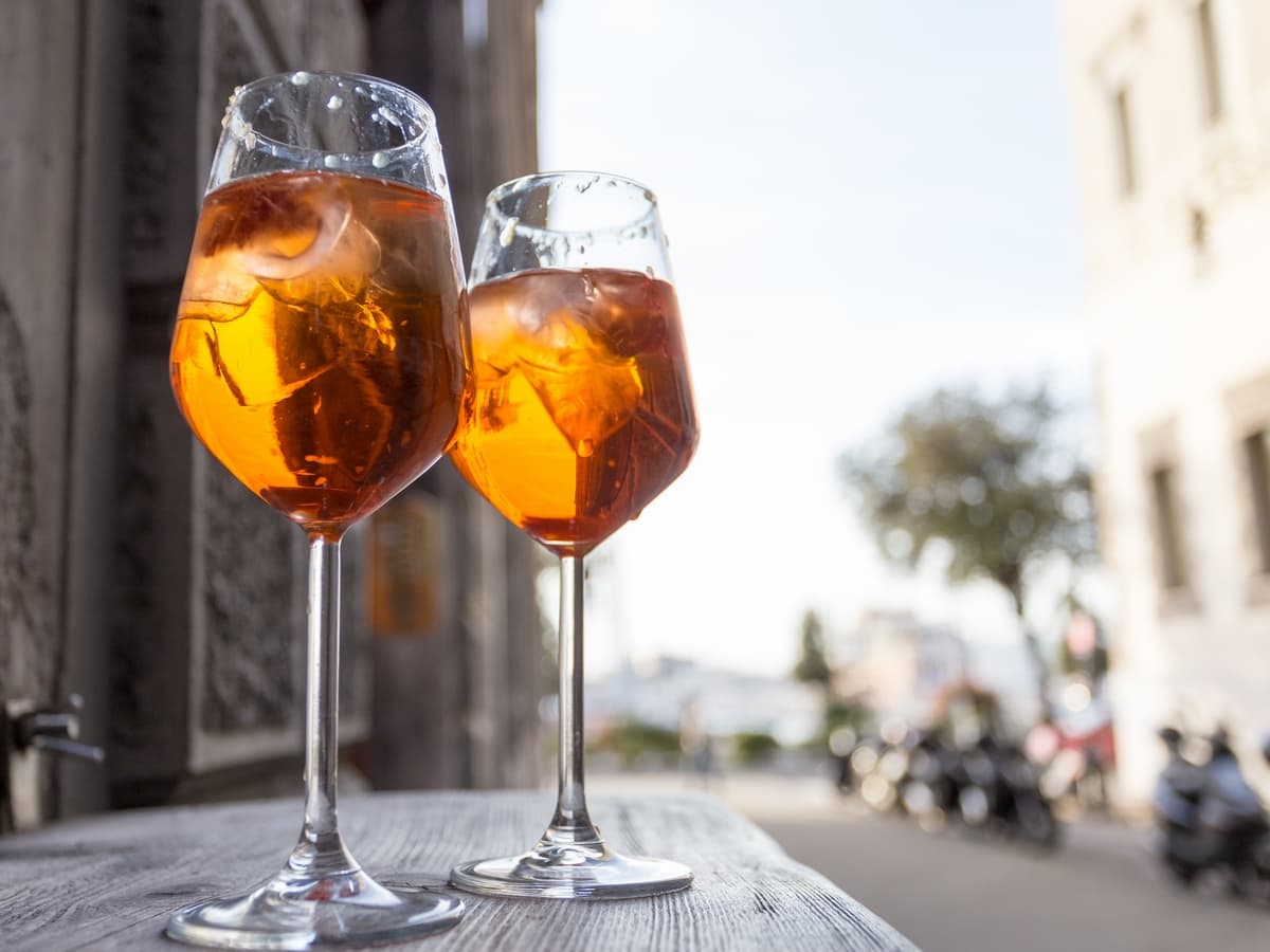 Two glasses filled with Aperol Spritz on the streets of Trieste.