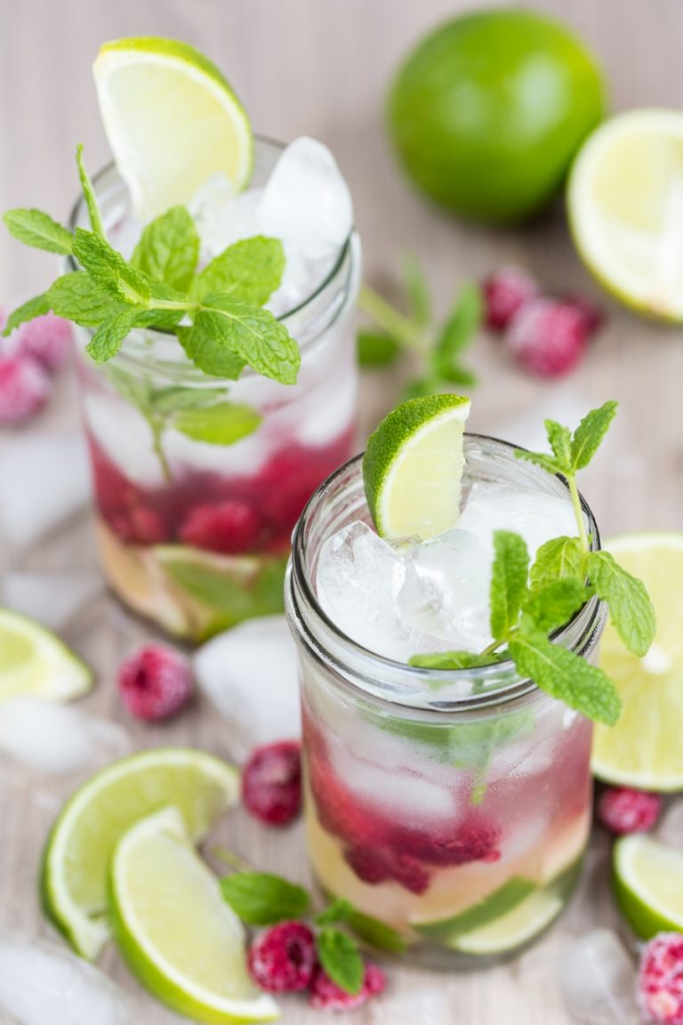 Two glasses of coconut water mojito with frozen raspberries.