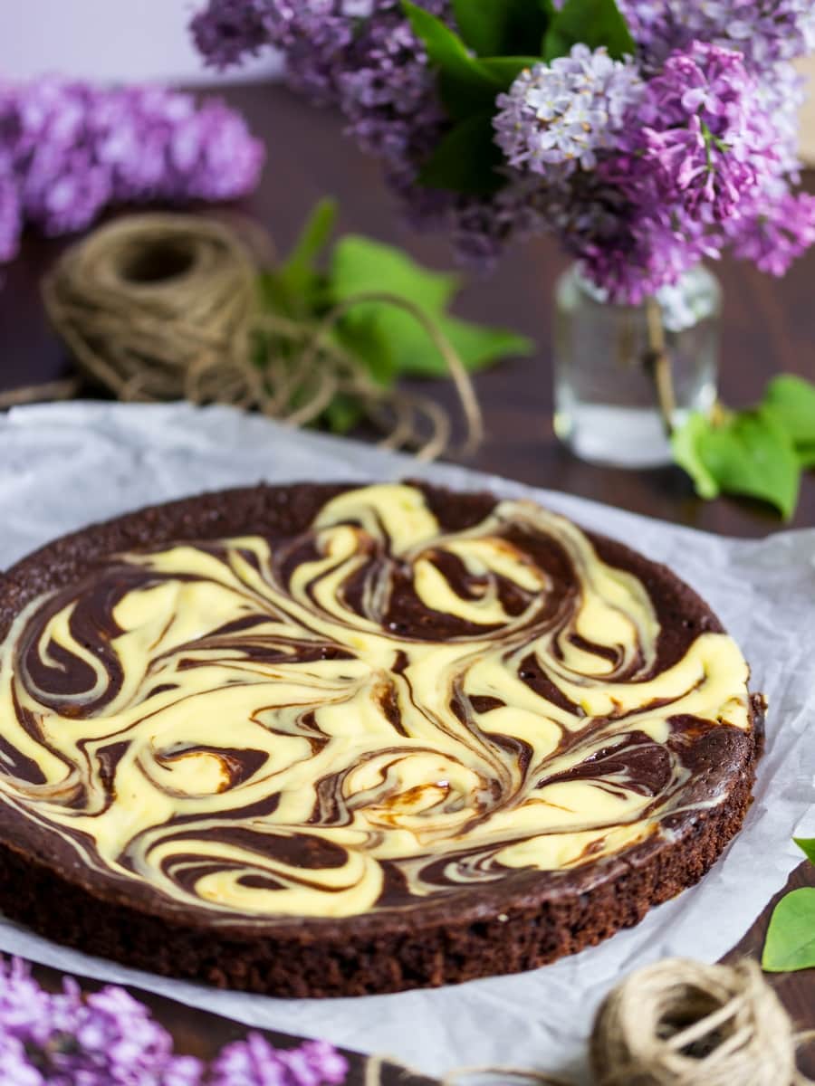 Chocolate cake with a cream cheese swirl, flowers in the background.