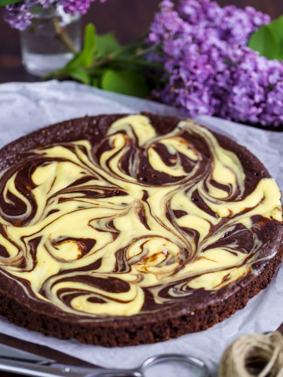 Chocolate cake with a cream cheese swirl, flowers in the background.