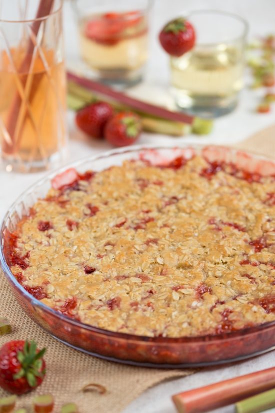 Baked strawberry rhubarb crisp, strawberry cocktails in the background.