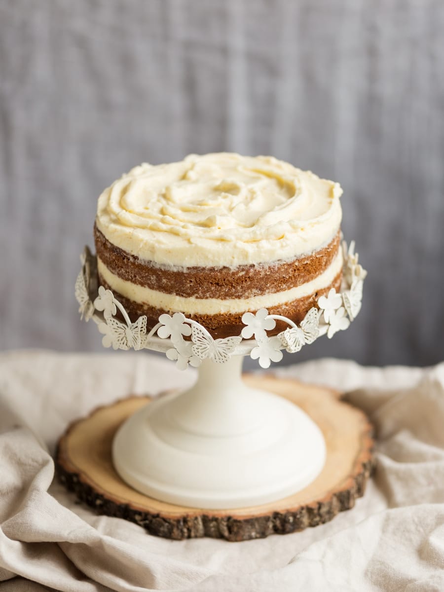 Frosted sweet potato cake on white cake stand.