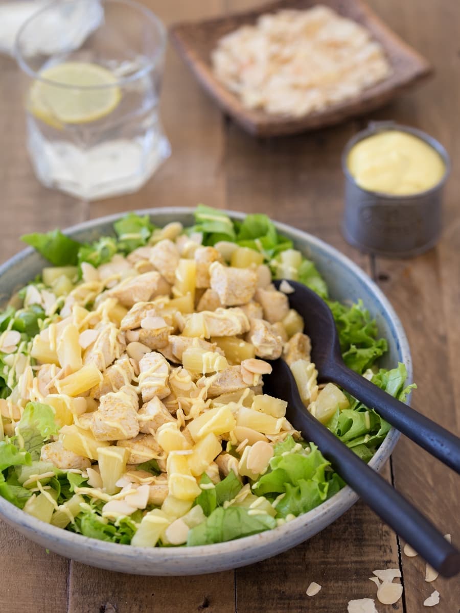 Chicken pineapple salad in a bowl with salad serving spoons in.