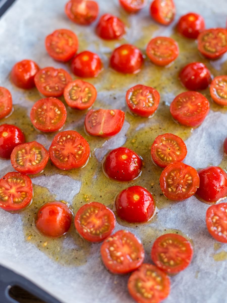 Raw cherry tomatoes on an oven tray about to get in the oven for roasting.