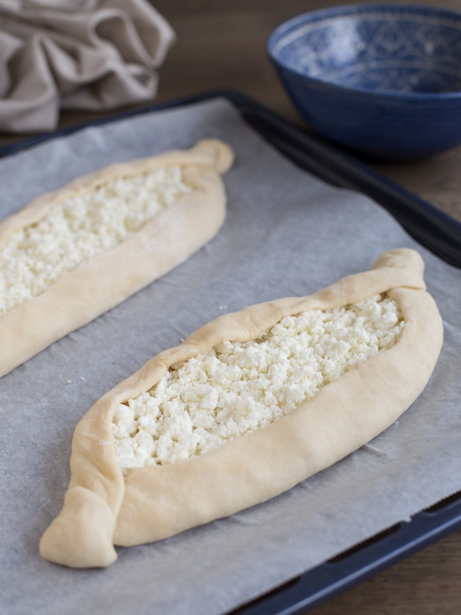 Traditional boat shaped khachapuri adjaruli before baking in the oven.