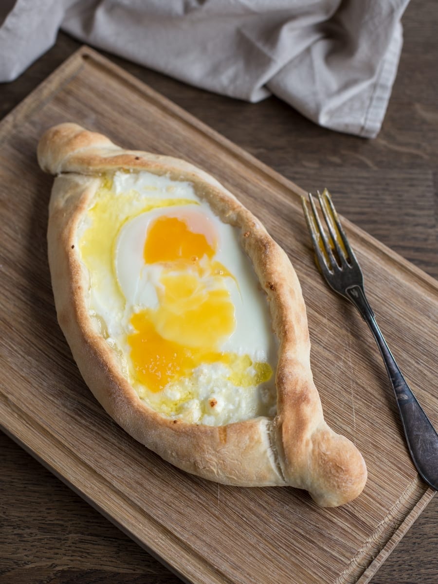 Fully baked adjaruli khachapuri with raw egg yolk on top.