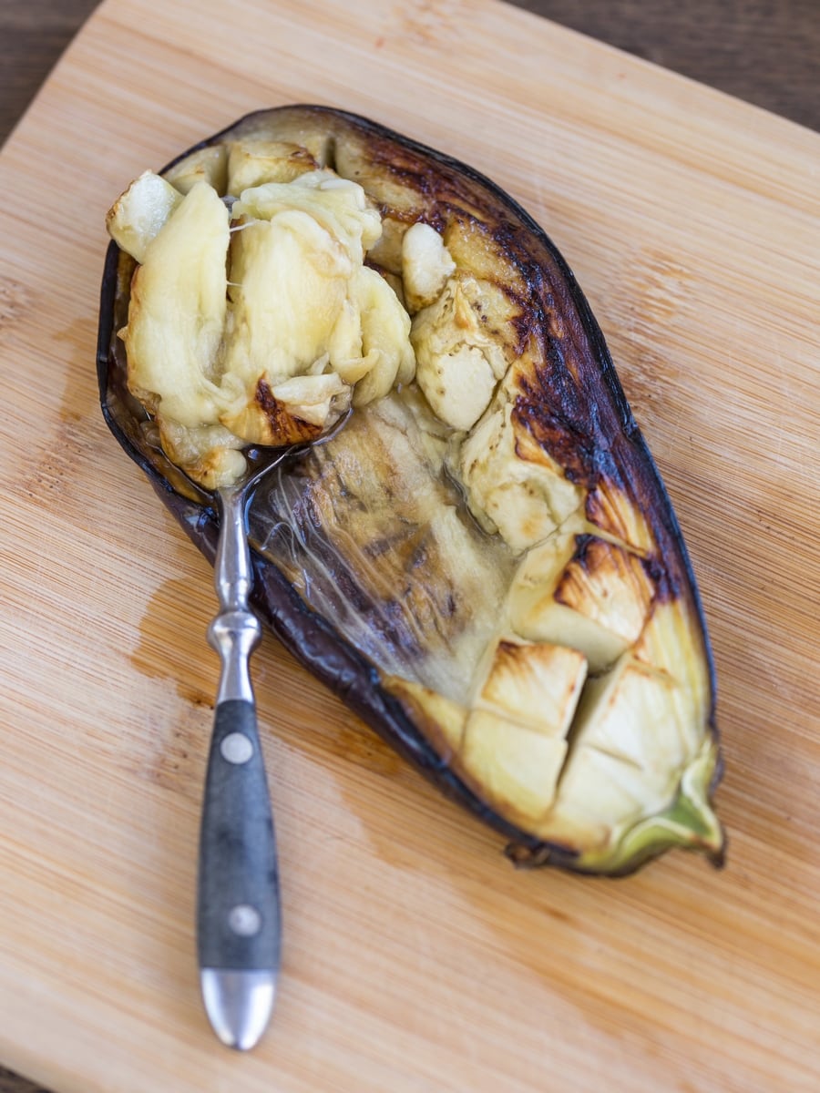 Spoonscooping up baked eggplant flesh.