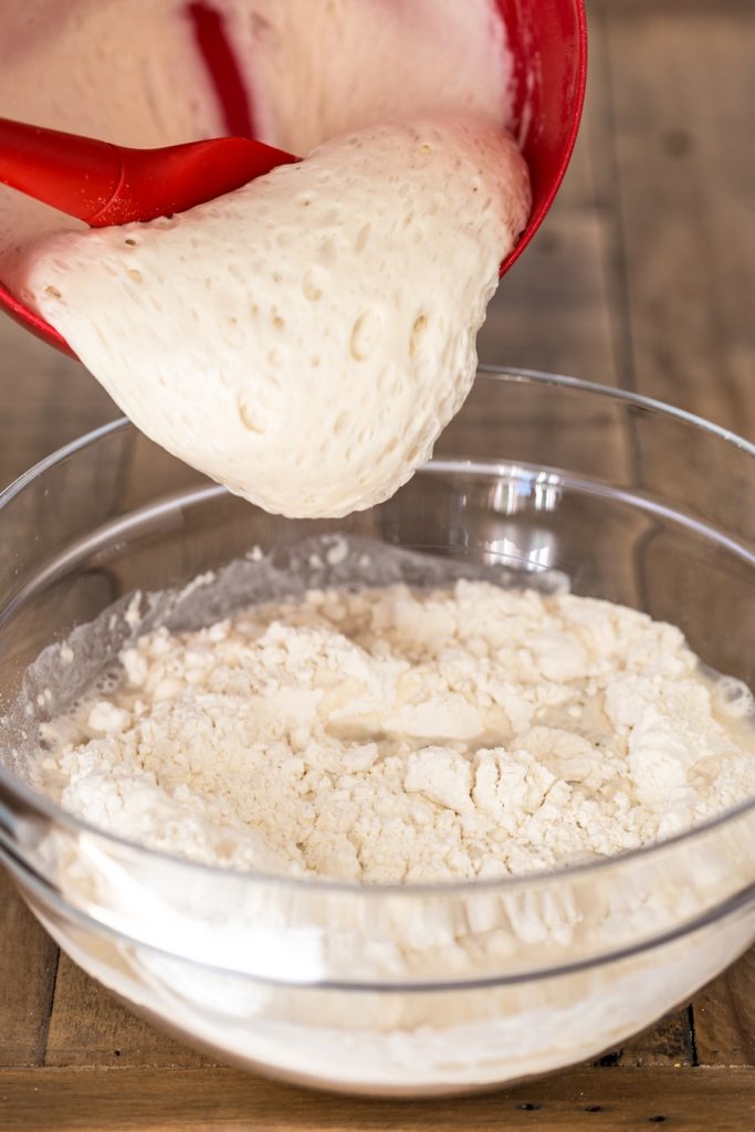 Mature poolish being poured over flour and water mixture.