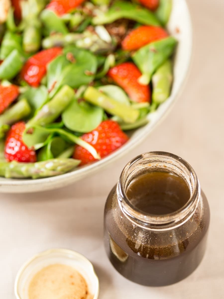 Balsamico vinaigrette dressing in a jar next to salad bowl.