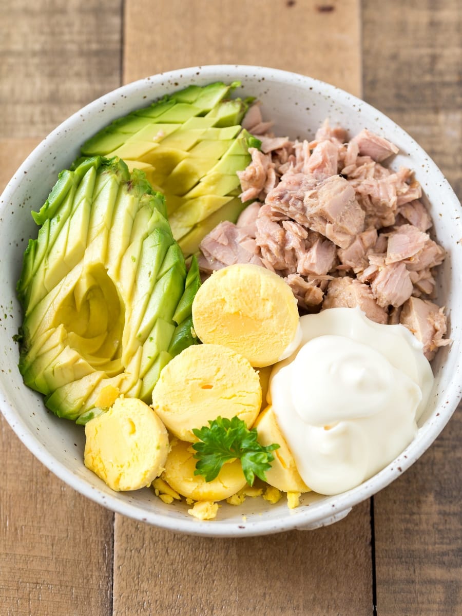 Avocado, egg yolks, tuna and mayonnaise in a bowl.