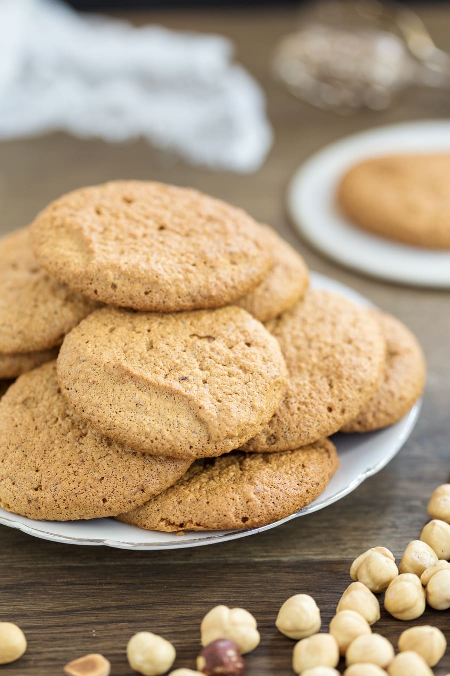 Honey hazelnut meringue cookies stacke on a white serving plate.