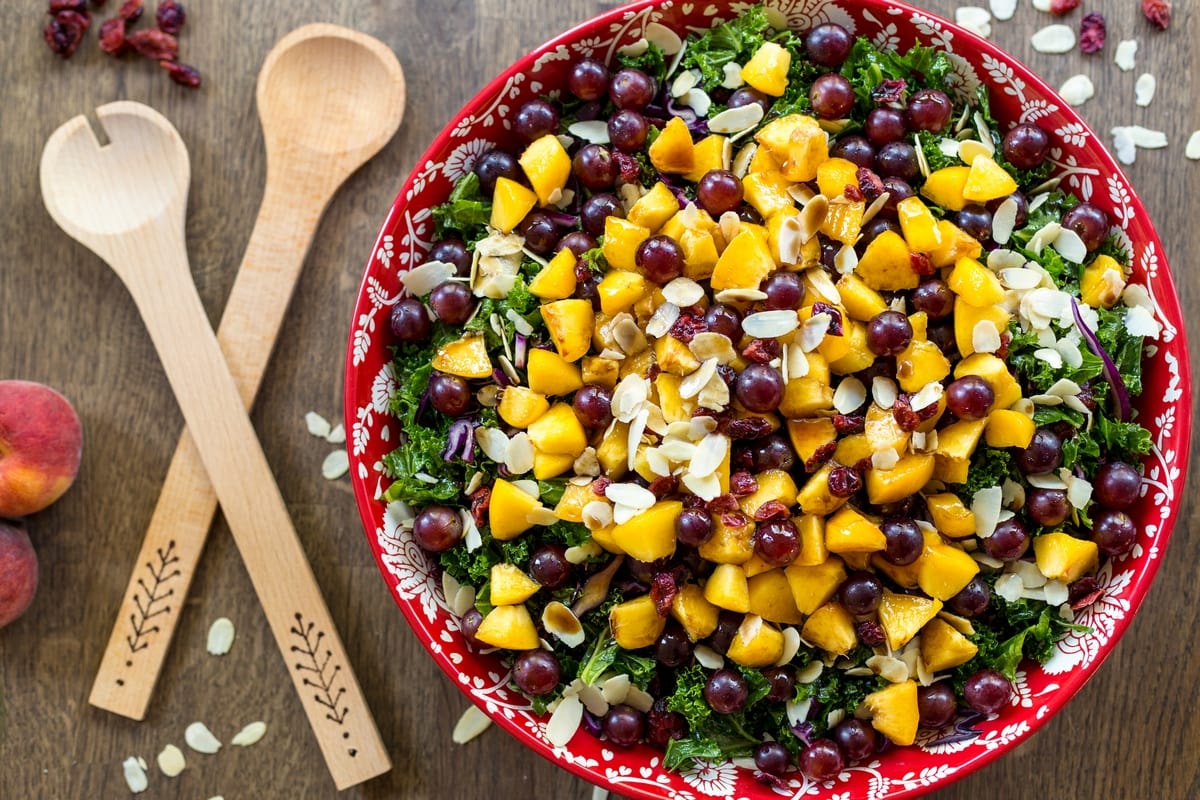 Fruity kale salad with peaches, grapes and almonds. With vegan balsamico dressing.