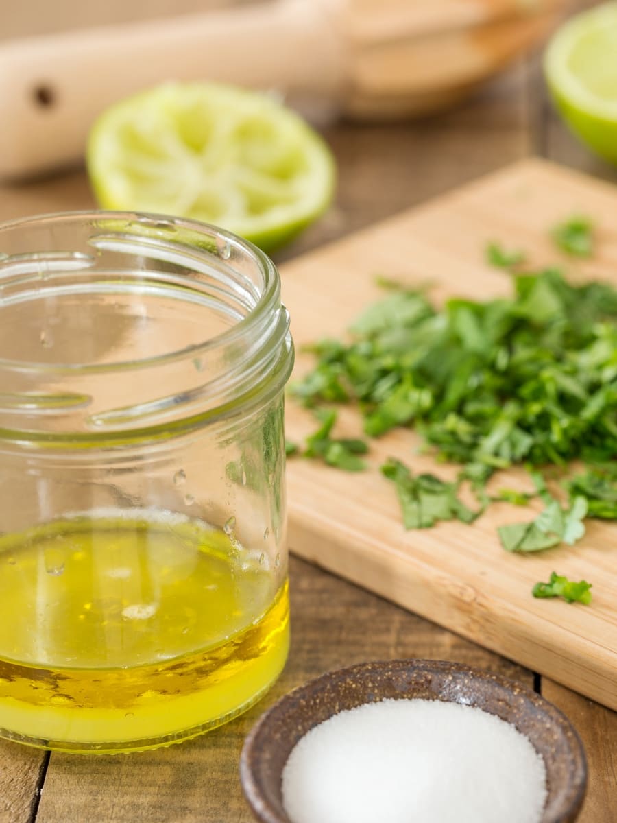 Succo di lime e olio d'oliva mescolati in un barattolo, coriandolo tritato e sale a parte.