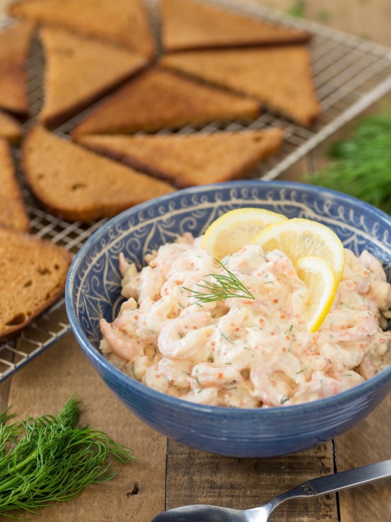 Swedish shrimp salad skagenröra in a bowl, toasted rye bread in the background.