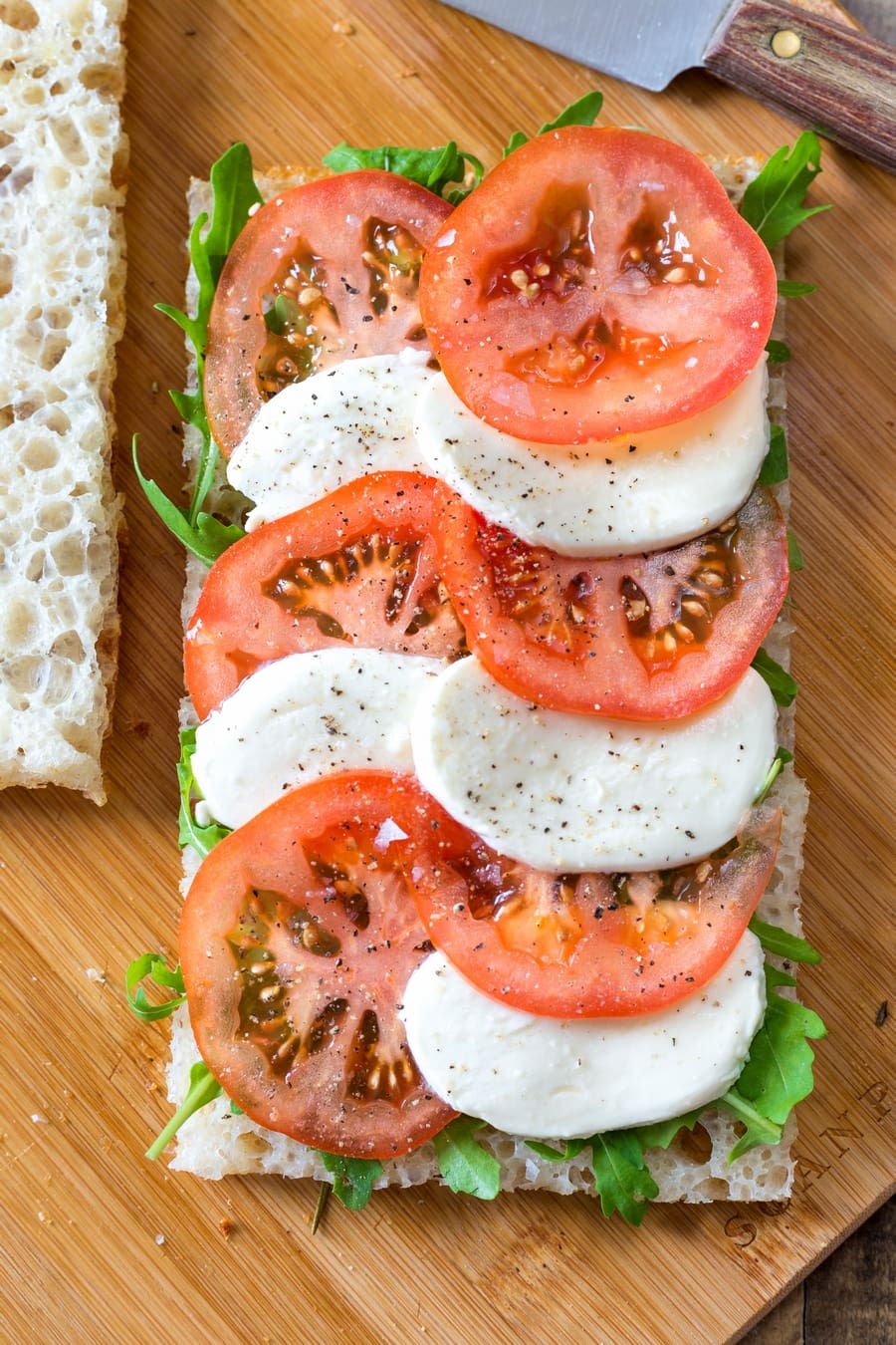 Caprese tomato and mozzarella slices on focaccia bread with rocket salad.
