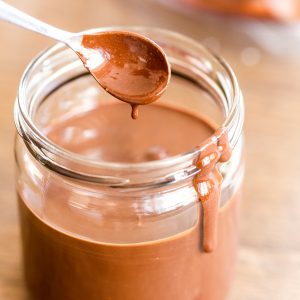 Homemade nutella in a jar, spoon being extracted.