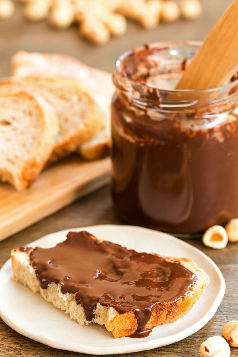 Homemade dark chocolate nutella spread on sourdough bread, jar behind it.