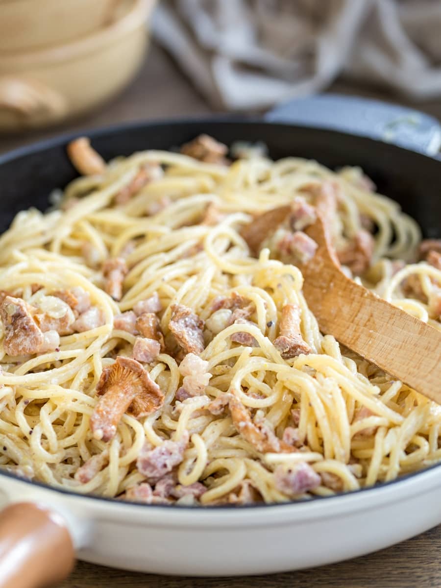 Creamy mustard pasta with bacon and mushrooms in a skillet.