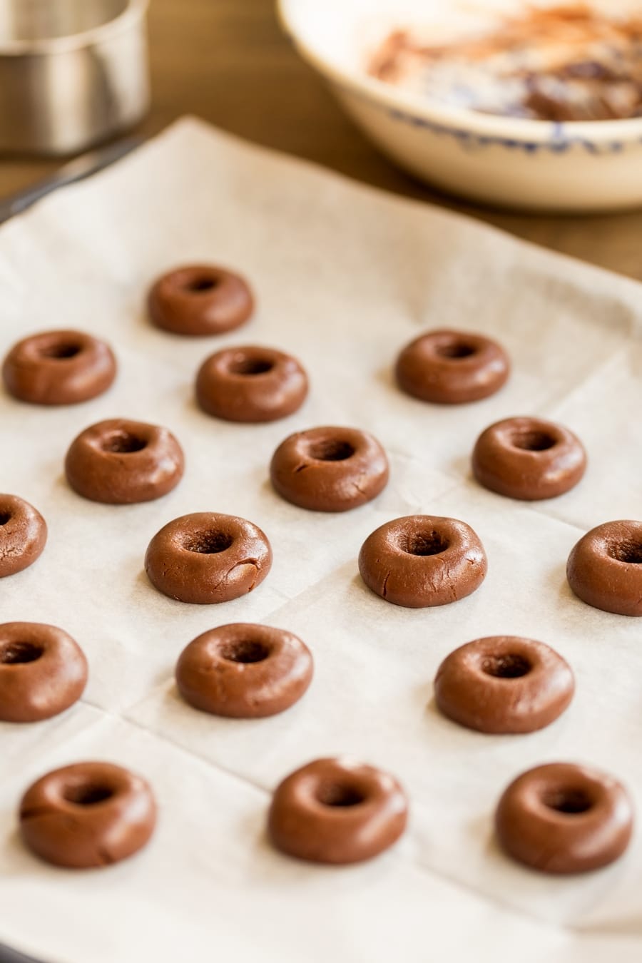 Unbaked nutellotti on a baking tray. They have been pressed in the midle to create the thumbprint cookie effect.