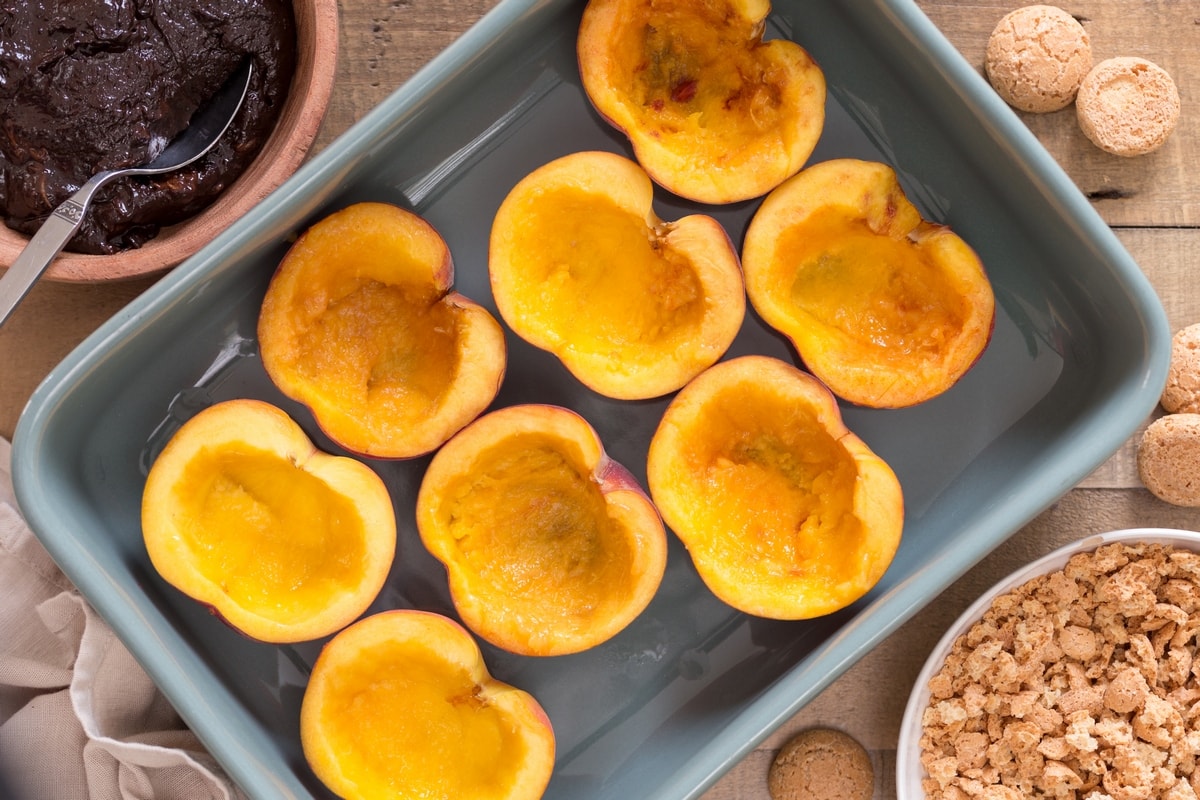 Carved halved peaches in an oven dish.