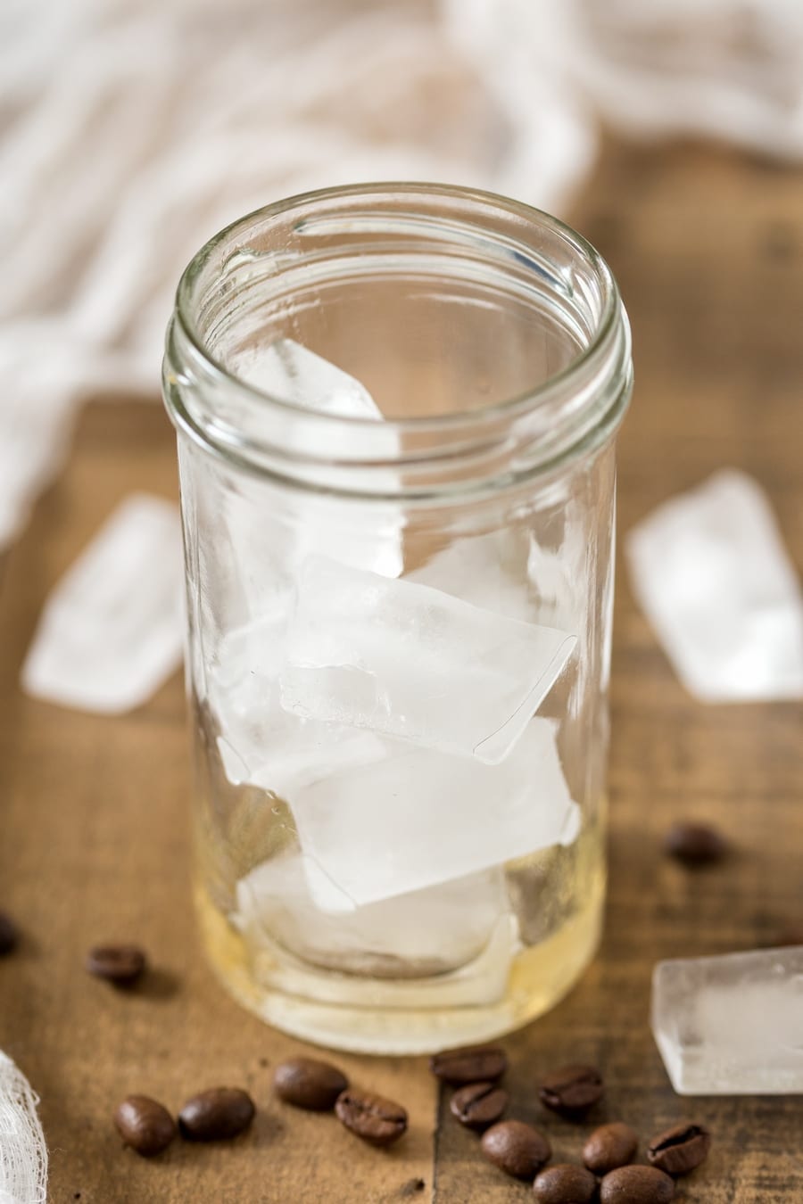 Vanilla syrup and ice cubes in a glass to make cardamom cold brew iced latte.