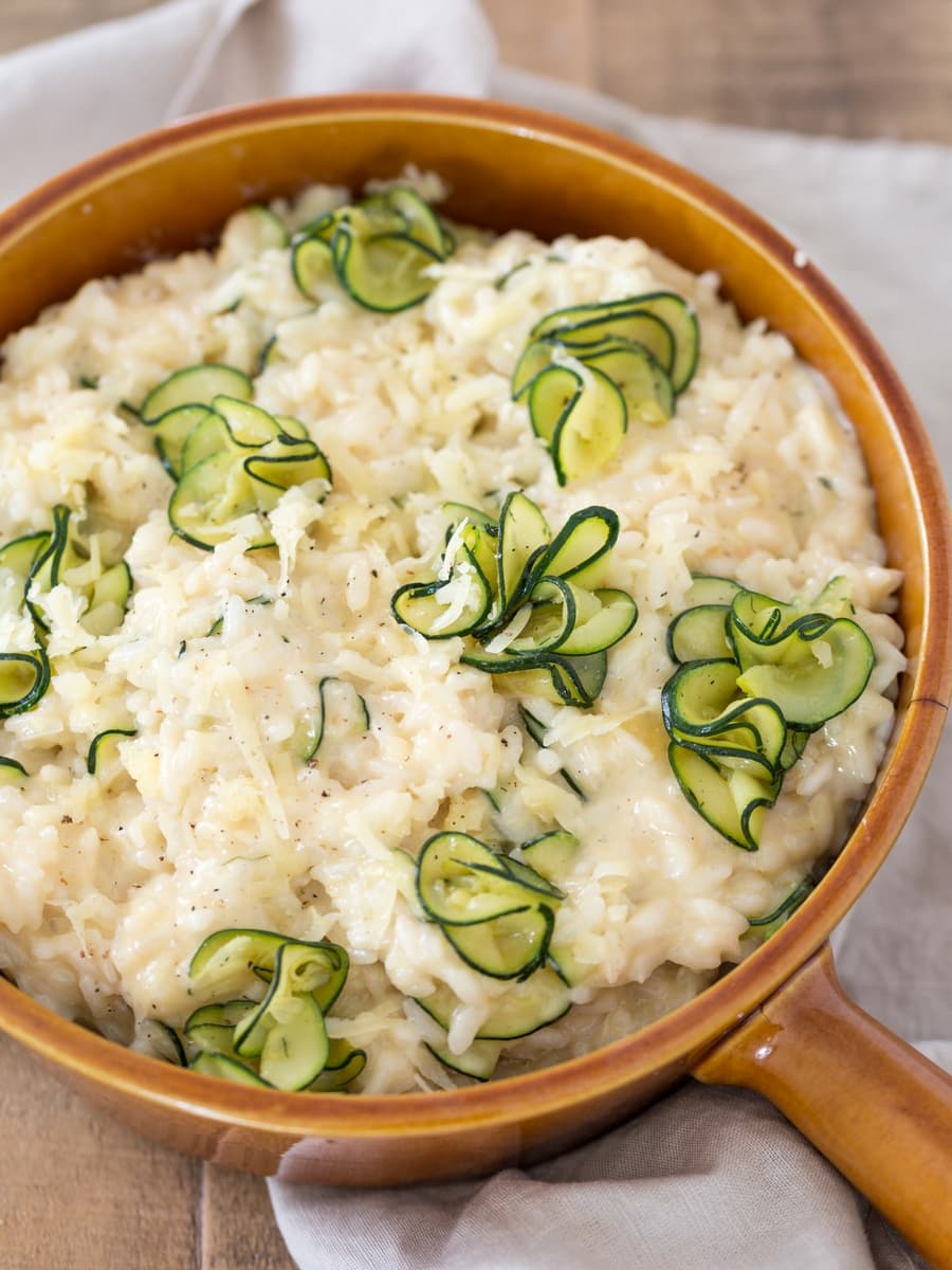 Zucchini cheddar risotto in a brown serving dish.