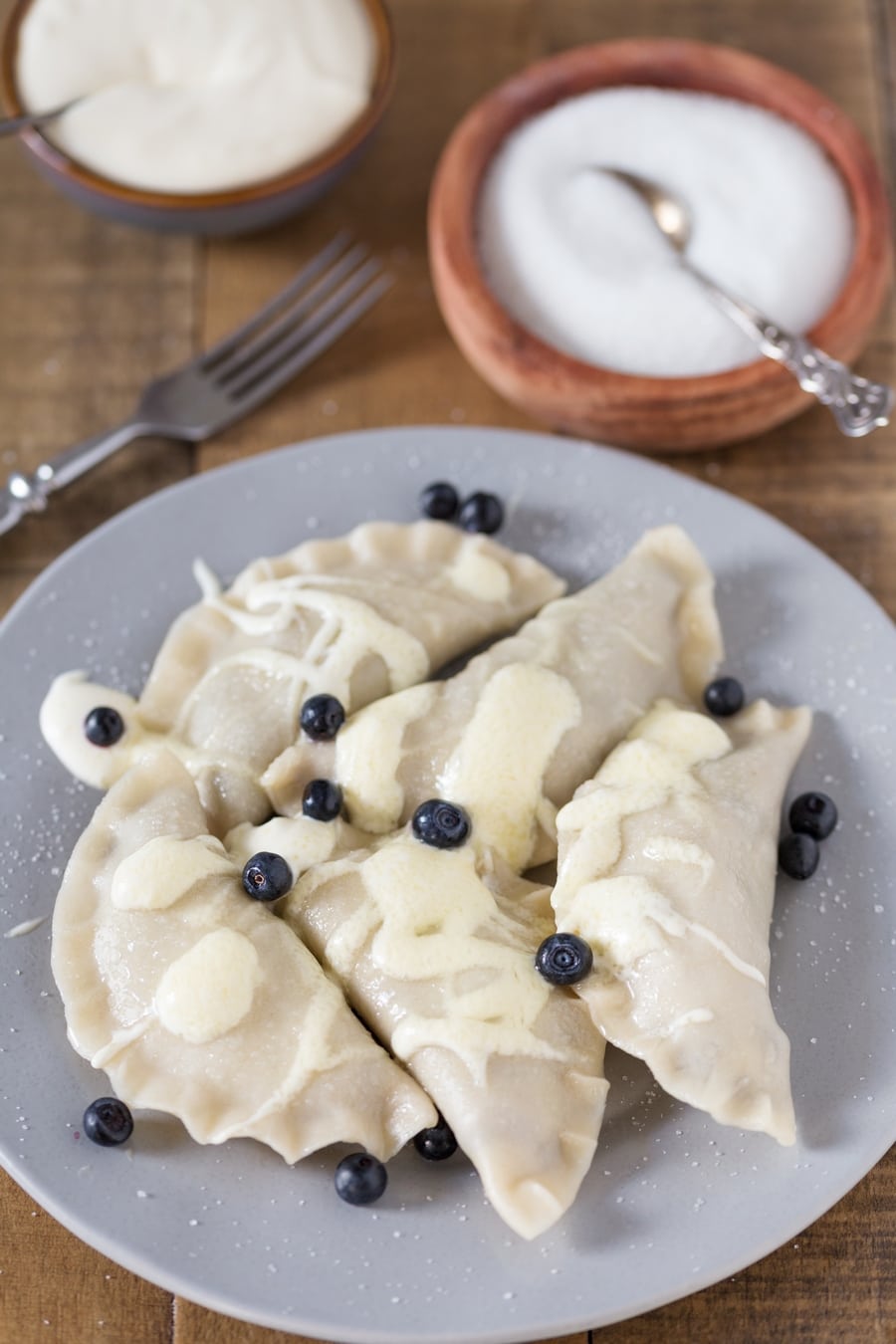 Cooked blueberry pierogi served with sour cream.