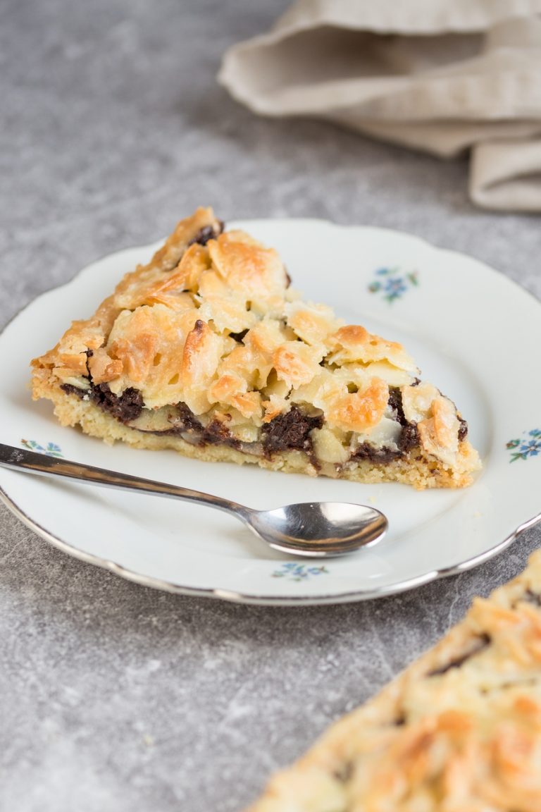 Almond chocolate tart on a gluten-free alond shortcrust. Filled with delicious dark chocolate and topped with glazed almonds, this chocolate almond tart is a delicious dessert option.