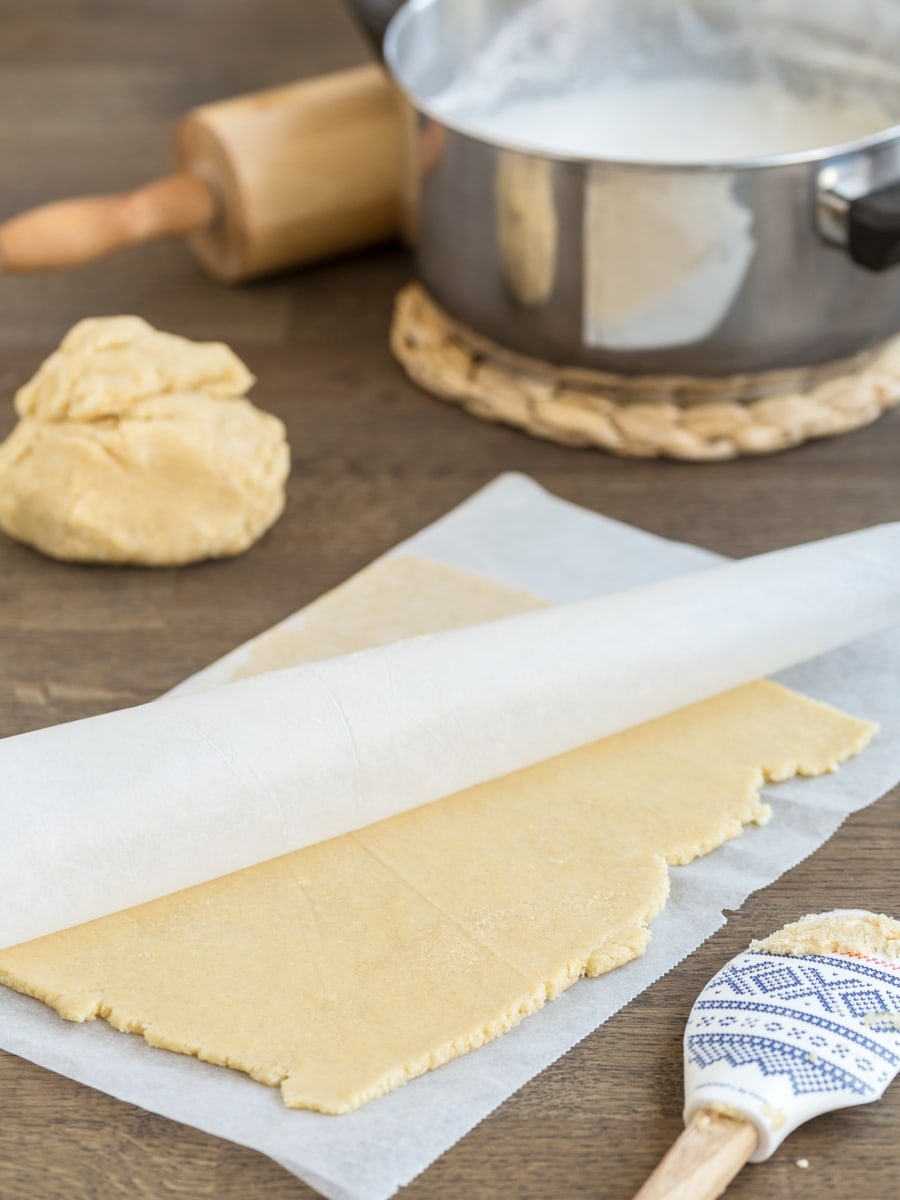 Rolled out honey shortcrust pastry etween parchment paper sheets.