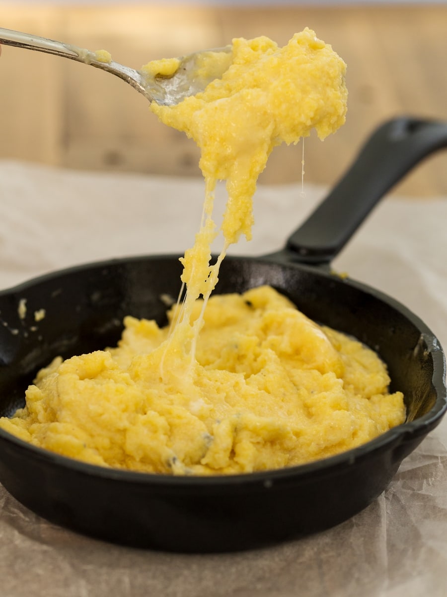 A spoonful of polenta concia pulling cheese strings.