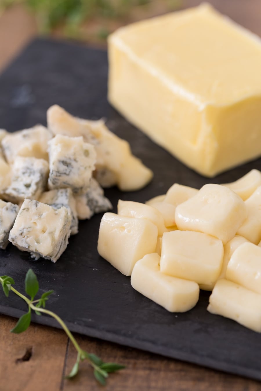 Cubes of taleggio and gorgonzola on a tray, butter in the background.