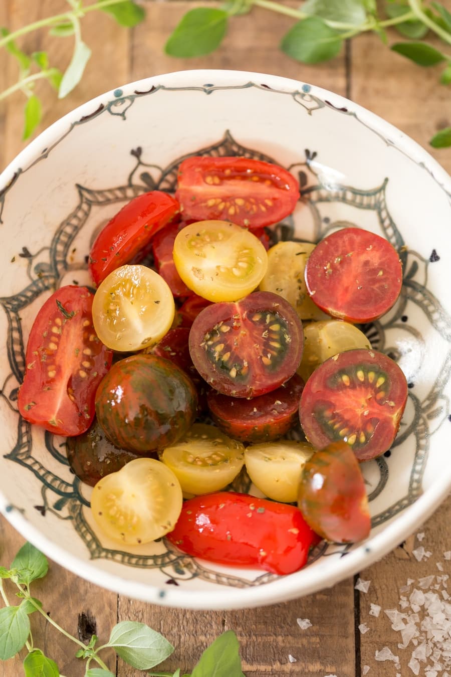 Halved cherry tomatoes in a bowl, seasoned with oil and oregano.