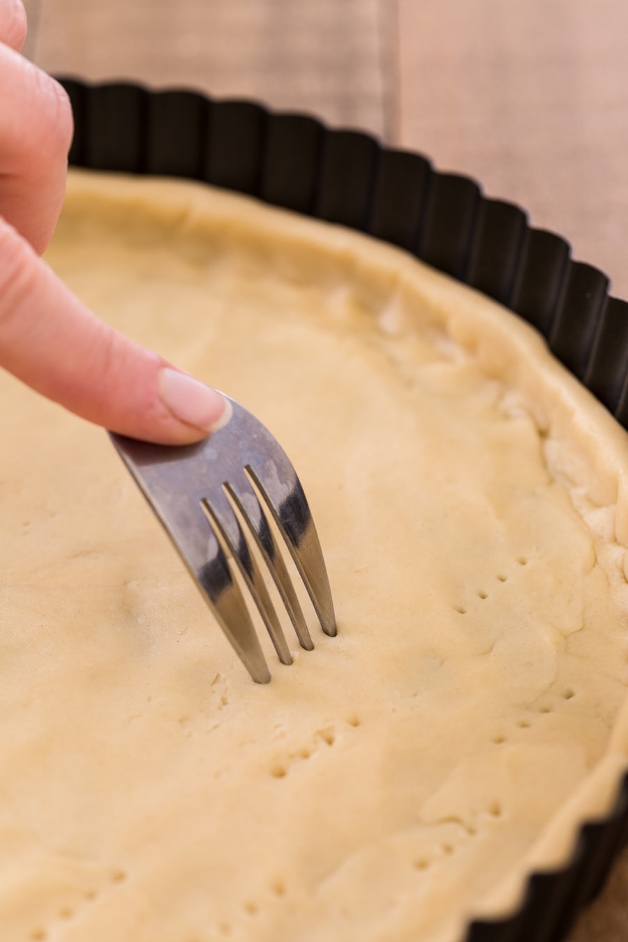 Pricking shortcrust bottom with a fork.