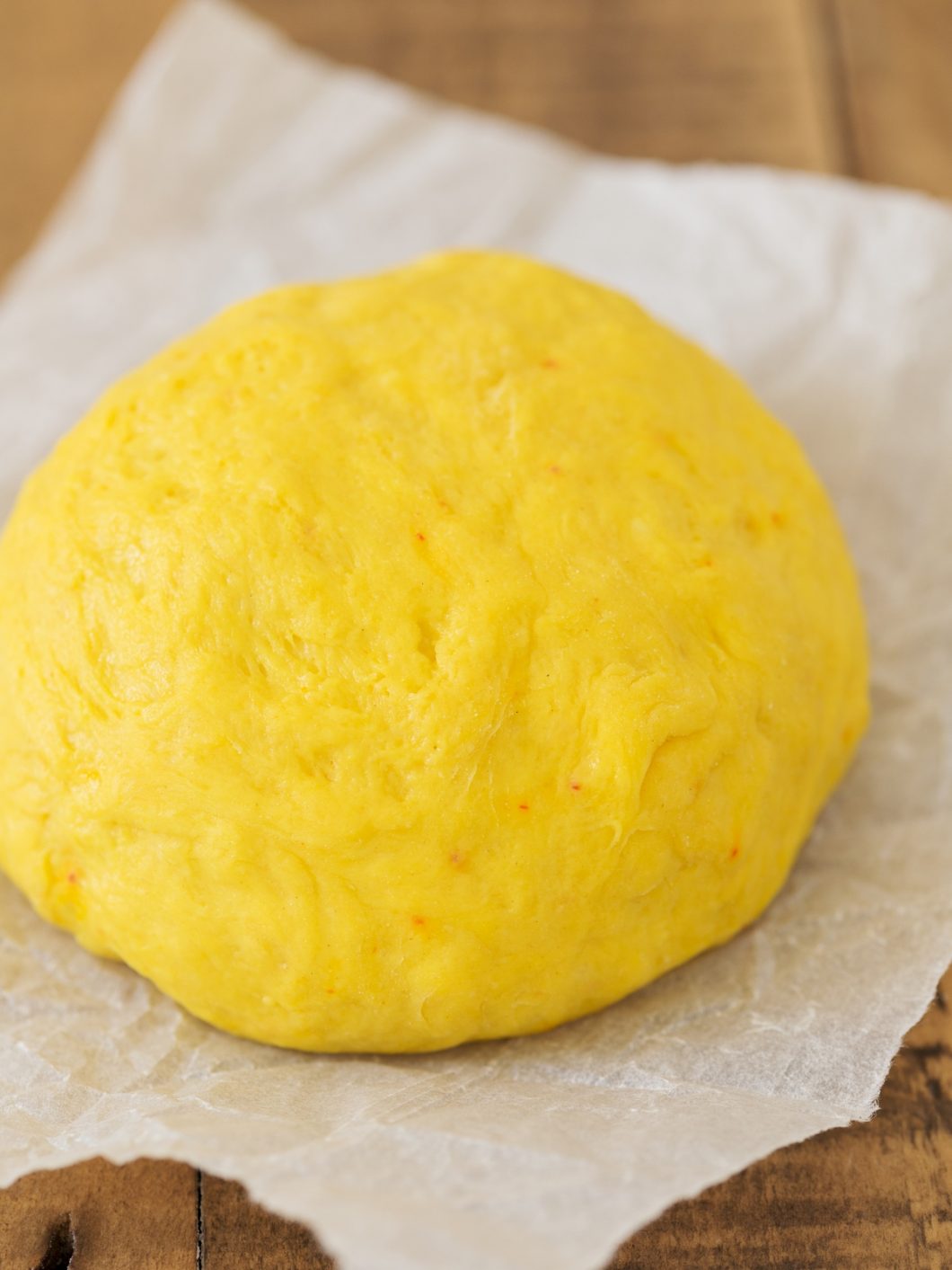 Ball of saffron bun dough resting on baking paper.