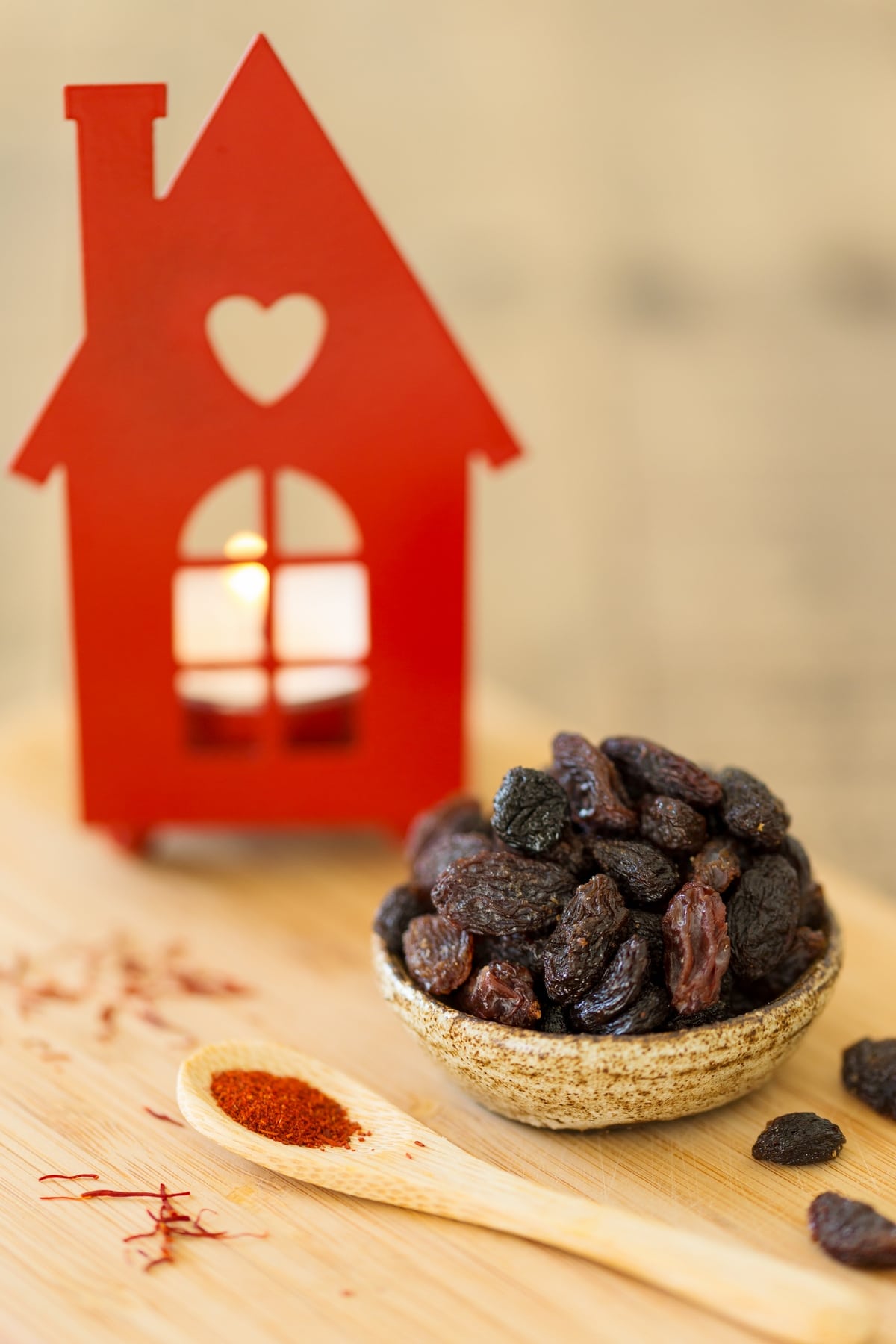 Bowl of raisins, saffron on a spoon, house-shaped candle holder.