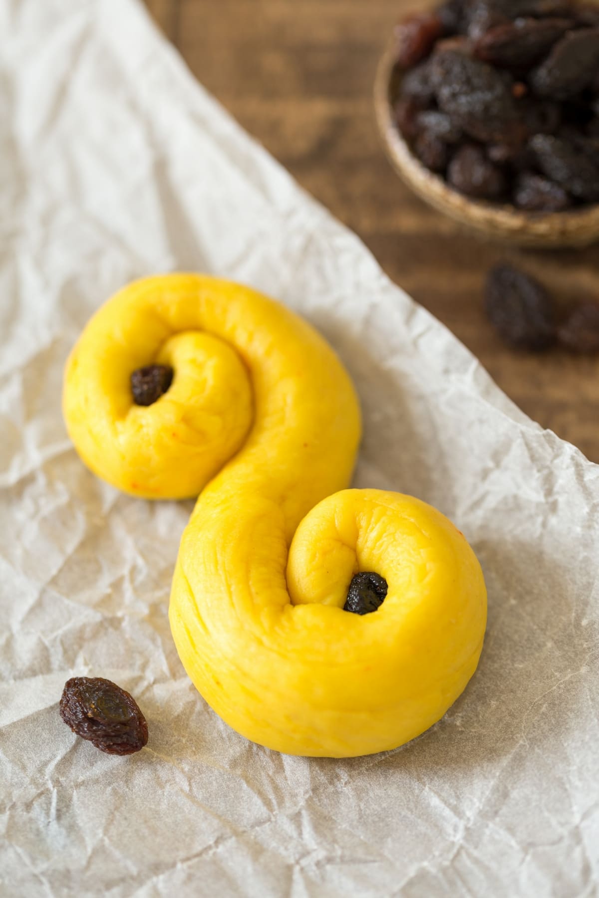 Unbaked Swedish saffron bun with raisins pressed in the swirls.