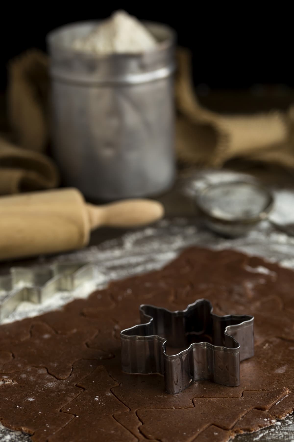 Snowflake shaped cookie cutter cutting out ginger thins.