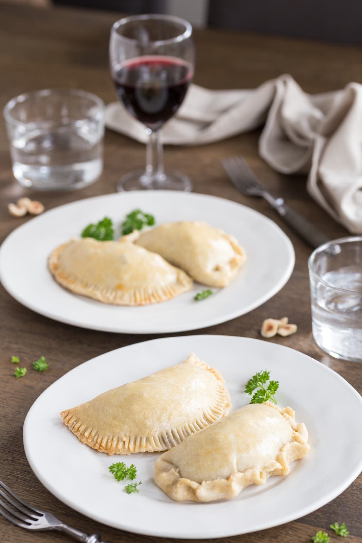 Baked empanada turnovers on white plates.