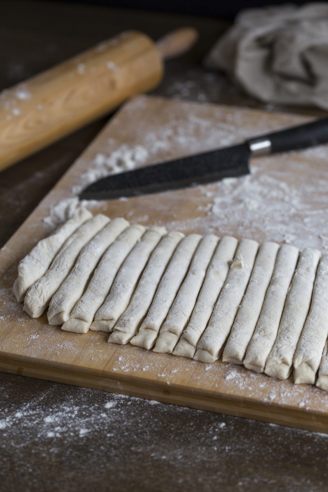 Folded dough being cut into strips.