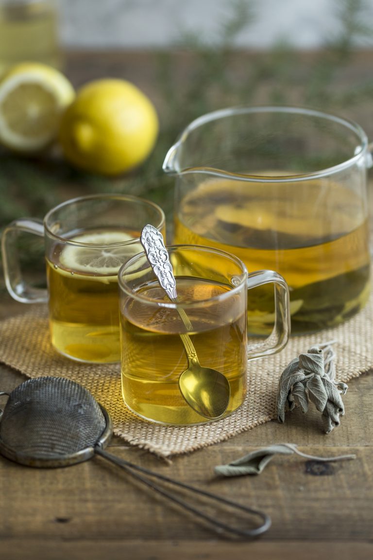 Lemon sage herbal tea in see-through jug and mugs.