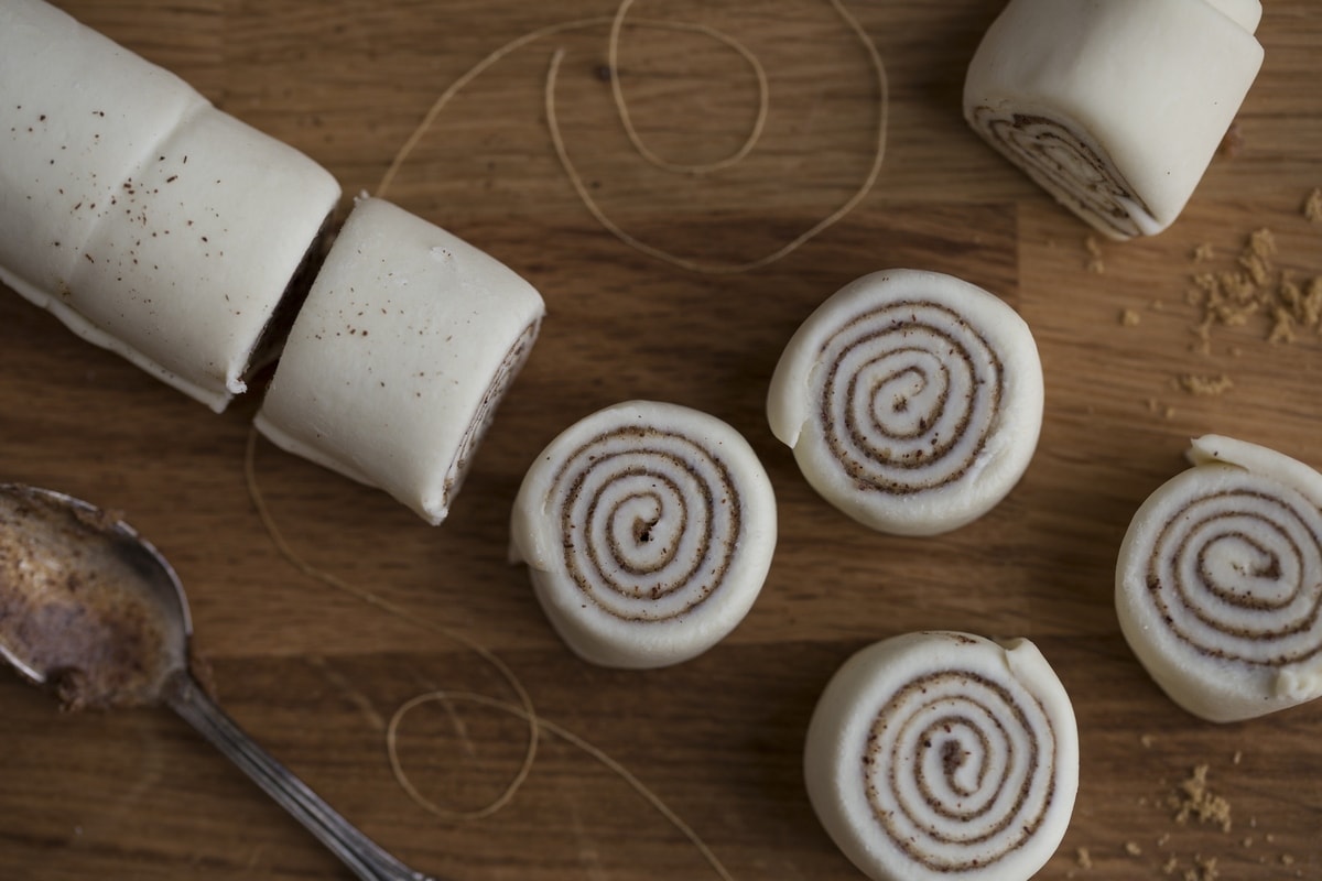 Cutting puff pastry cinnamon pinwheels with a thread.