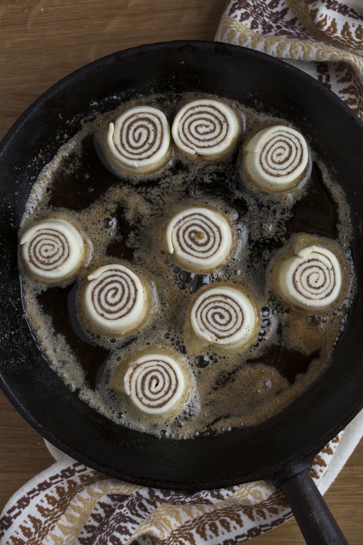 Cooking puff pastry cinnamon rolls in a skillet.