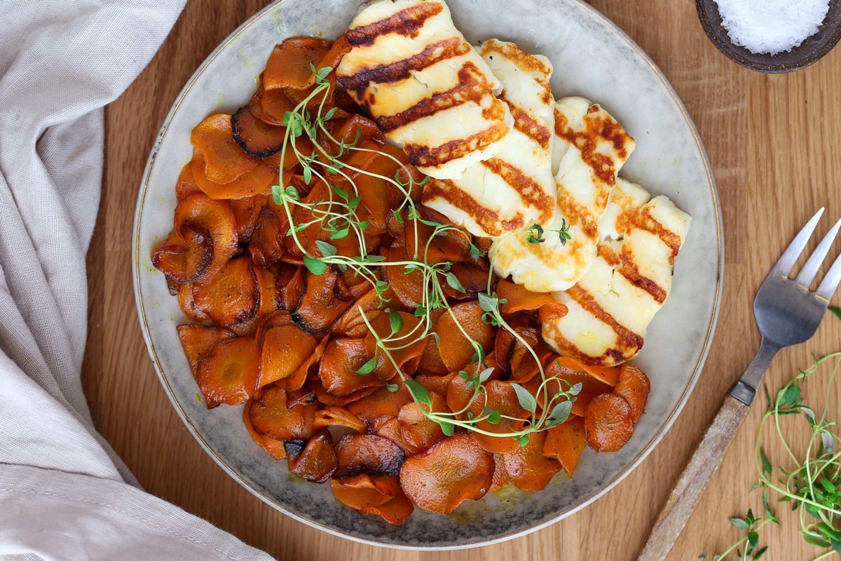 A portion of butter sauteed carrots with fresh thyme and grilled halloumi.