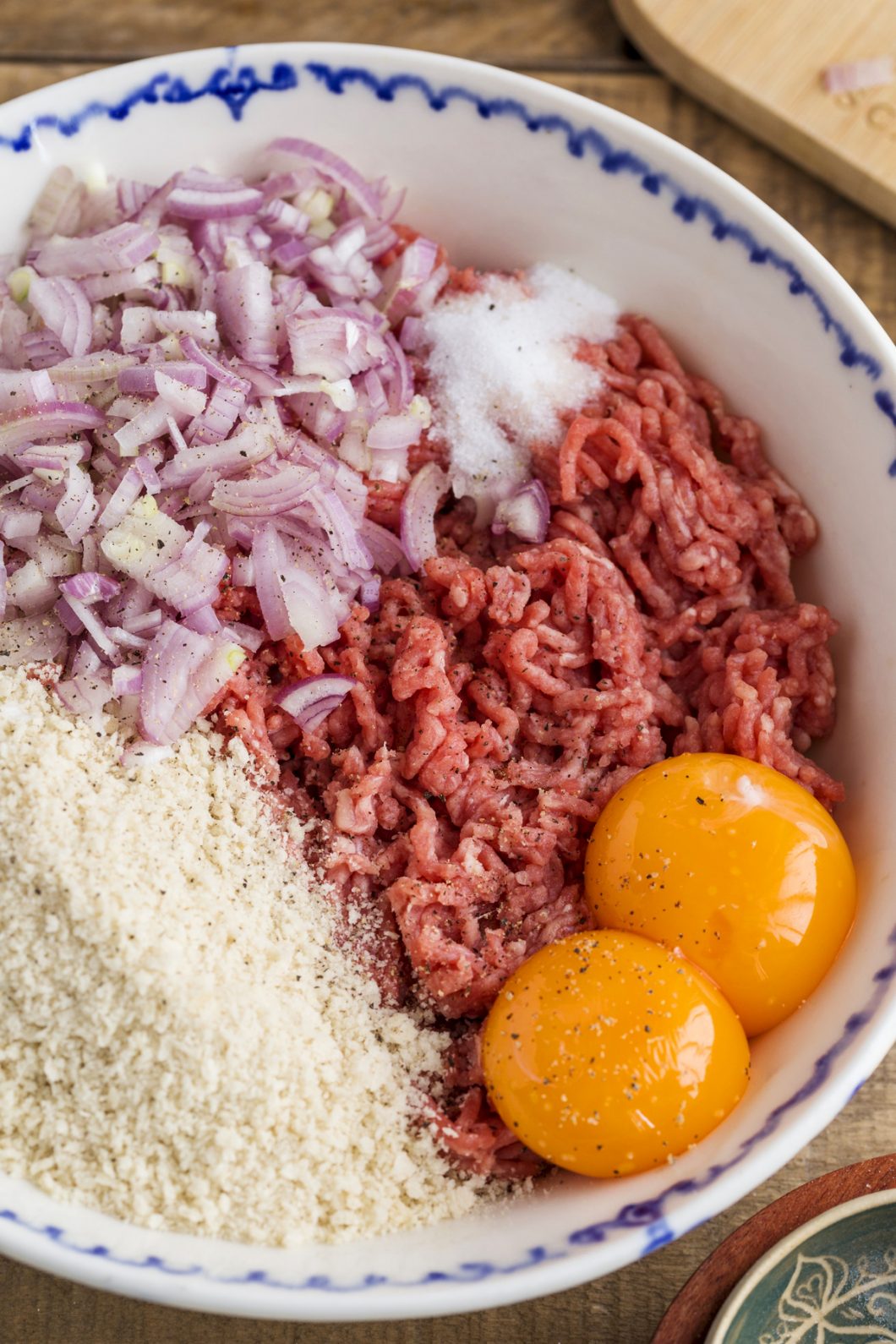 One bowl with ground meat, egg yolks, breadcrumbs, minced onion, salt and pepper.